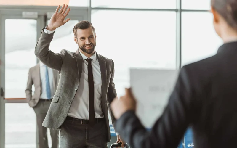 businessman waving to partner who waiting for him with name sign