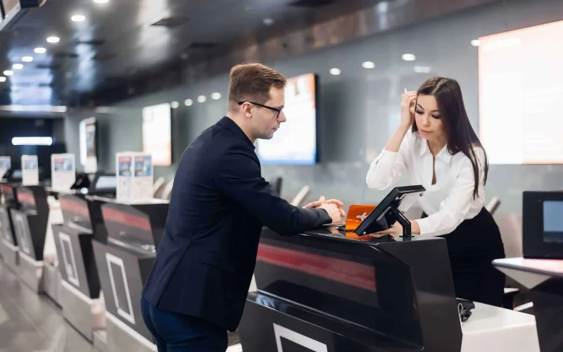 Staff At Airport Check In Desk Handing Ticket To Businessman